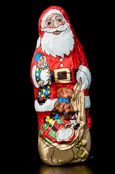 Chocolate Santa Claus standing on dark wooden table with reflection