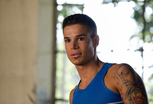 Handsome young man with blue tanktop and tattoo