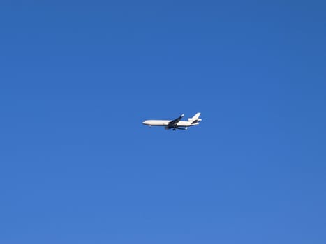 White airplane in the blue sky, coming in for landing