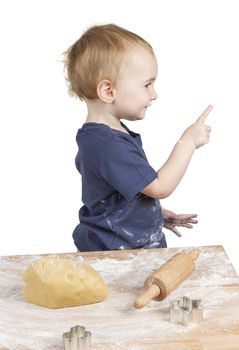 young child making cookies pointing at side