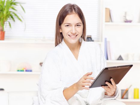 girl in bathrobe at home with touch pad computer