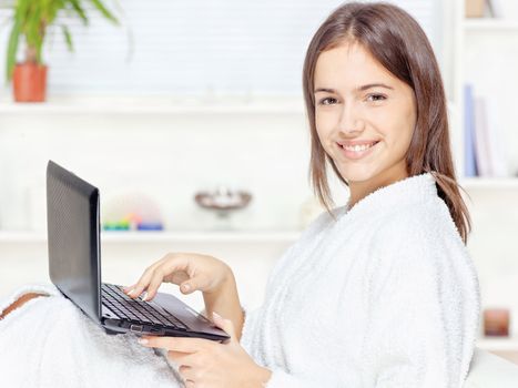 girl in bathrobe at home with computer