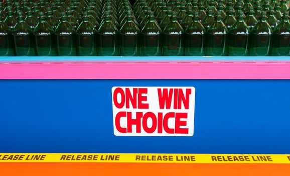 A game at the boardwalk where you toss rings trying to land them around the necks of bottles. The photo has rows of bottles as well as a sign that says One Win Choice in a colorful display.