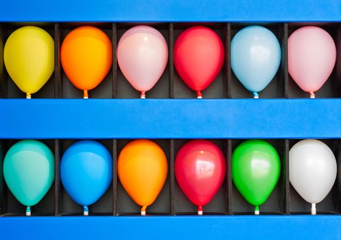 A blue wall case with colorful balloons. Photo is of a boardwalk arcade game. Only the case and balloons are shown.