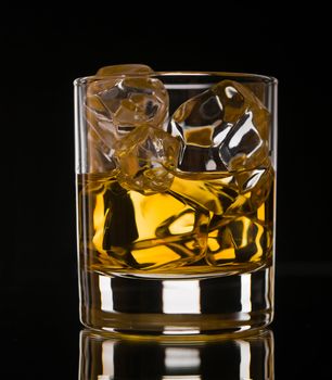 Glass of whiskey on the rocks on black background