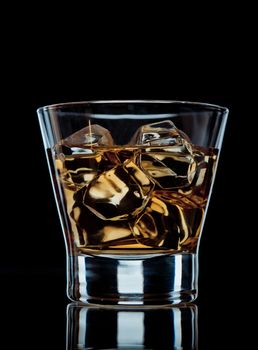 Glass of whiskey on the rocks on black background