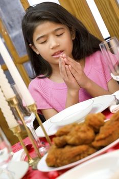 Little girl saying a prayer during dinner mealtime