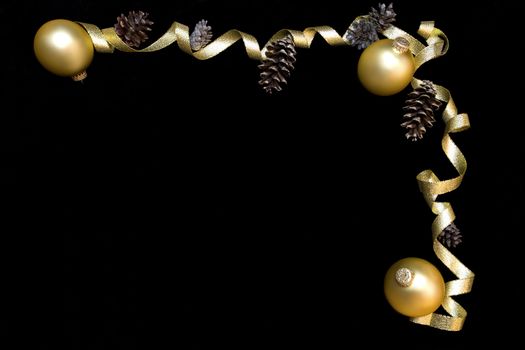 Gold ornaments and gold ribbon on black background framing space for text