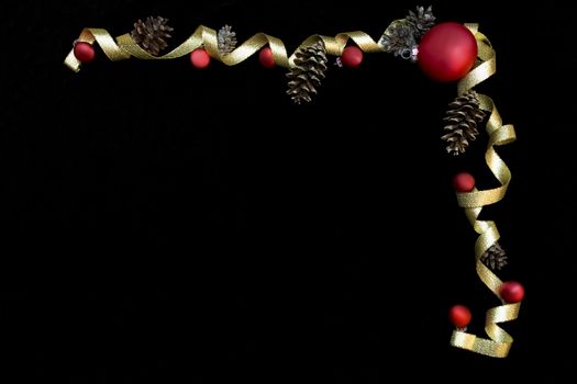 Red ornaments and gold ribbon on black background framing space for text