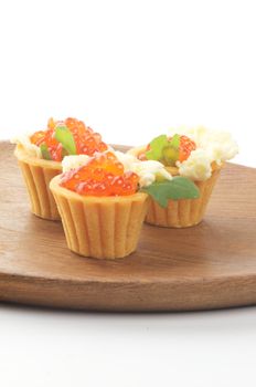 Tartlets with Perfect Red Caviar, Greens and Butter on Wooden Plate closeup 