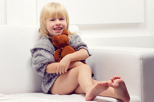 Little girl with bear on white sofa