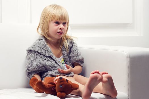 Little girl with bear on white sofa