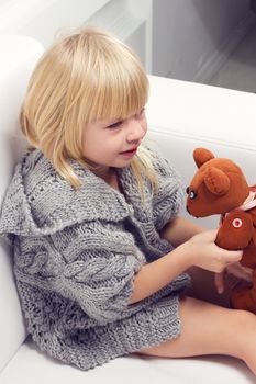 Little girl with bear on white sofa