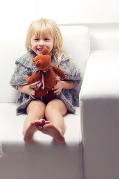 Little girl with bear on white sofa