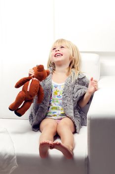 Little girl with bear on white sofa