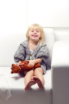 Little girl with bear on white sofa