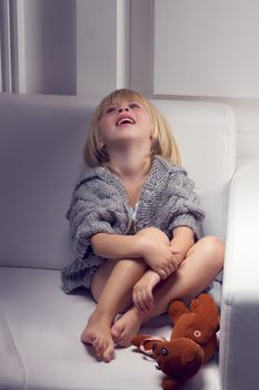 Little girl with bear on white sofa