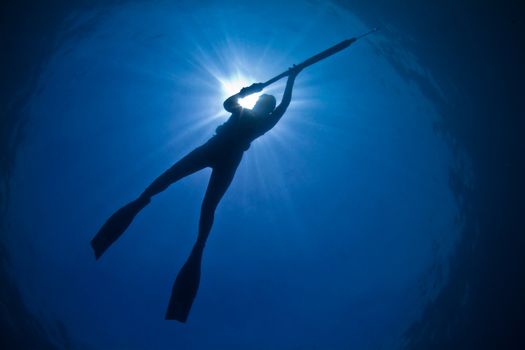 A young woman silently stalks her pray in the deep blue waters of Australia's Great Barrier Reef.