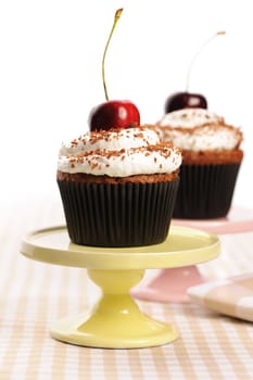 Cupcakes with whipped cream and cherry on a table