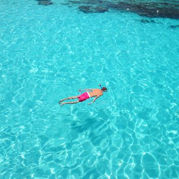 Man snorkeling in crystal clear turquoise water at tropical beach