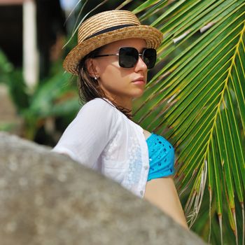 Woman in sunglasses near palm tree wearing hat