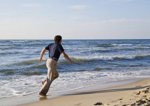 Man running along seashore on a sunny summer day