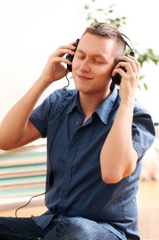 Portrait of young man listening music at home
