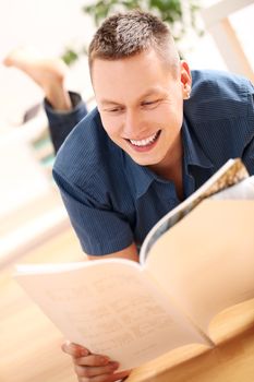 Portrait of Young man reading magazine at home