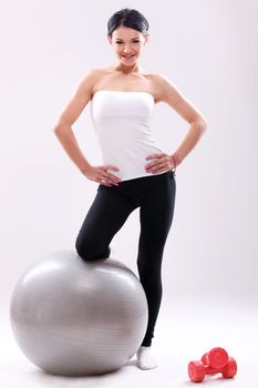 Cute young fitness girl with abs ball in studio