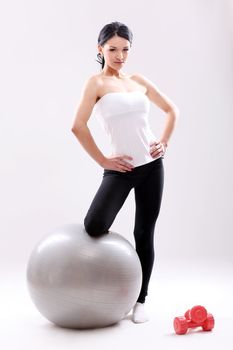 Cute and young fitness girl with abs ball in studio