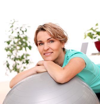 Cute and smiling middle aged woman with abs ball at home