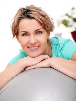 Cute and smiling middle aged woman with abs ball at home