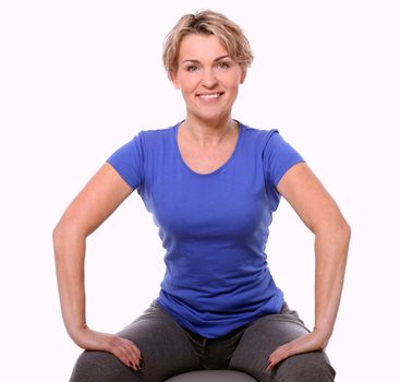 Cute and smiling middle aged woman with abs ball in studio