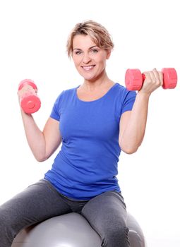 Cute mid aged women do exercises with dumbbells on a abs ball