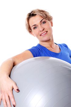 Cute and smiling middle aged woman with abs ball in studio