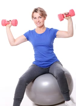 Cute mid aged women do exercises with dumbbells on a abs ball