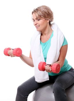 Cute mid aged women with towel do exercises with dumbbells ona a ball