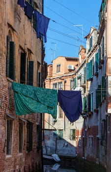 Clothes hanging out to dry between the buildings over a small canal in Venice,Italy.