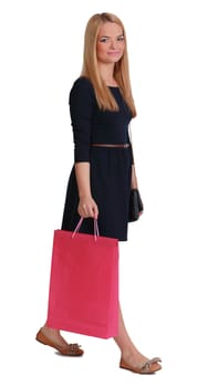 Young blonde woman with a pink shopping bag walking against a white background.