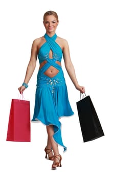 Young blonde woman in a fancy dress with shopping bags walking to the camera against a white background.