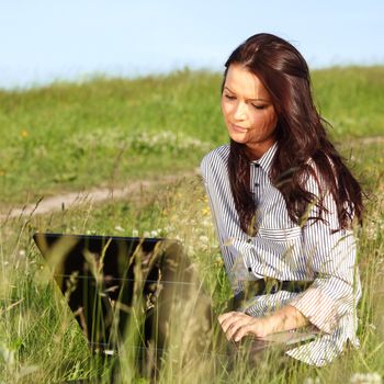 girl with laptop on green grass