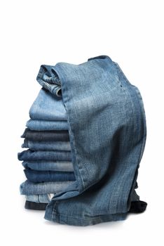 Stack of old and worn blue jeans over a white background