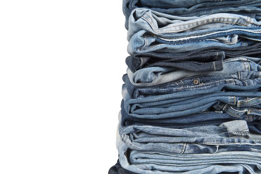 Stack of old and worn blue jeans over a white background