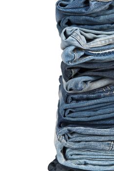 Stack of old and worn blue jeans over a white background