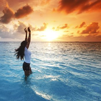 Beautiful woman in sea enjoying colorful sunset