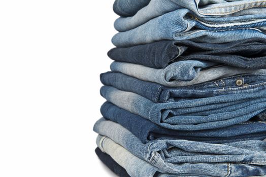 Stack of old and worn blue jeans over a white background