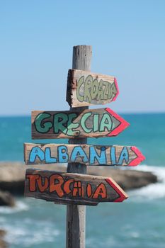 Italian wooden arrow signpost indicating directions for Croatia, Greece, Albania, Turkey
