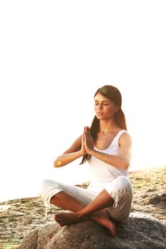 Young woman practicing yoga  near the ocean