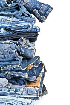 Stack of old and worn blue jeans over a white background