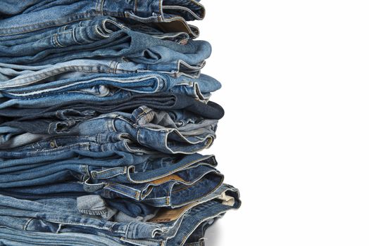 Stack of old and worn blue jeans over a white background